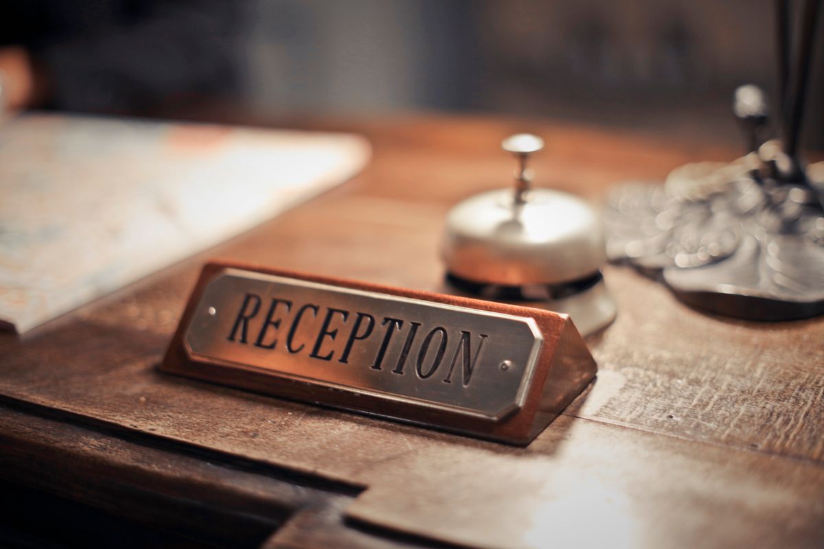 A reception sign and a service bell on a counter, nobody behind it.
