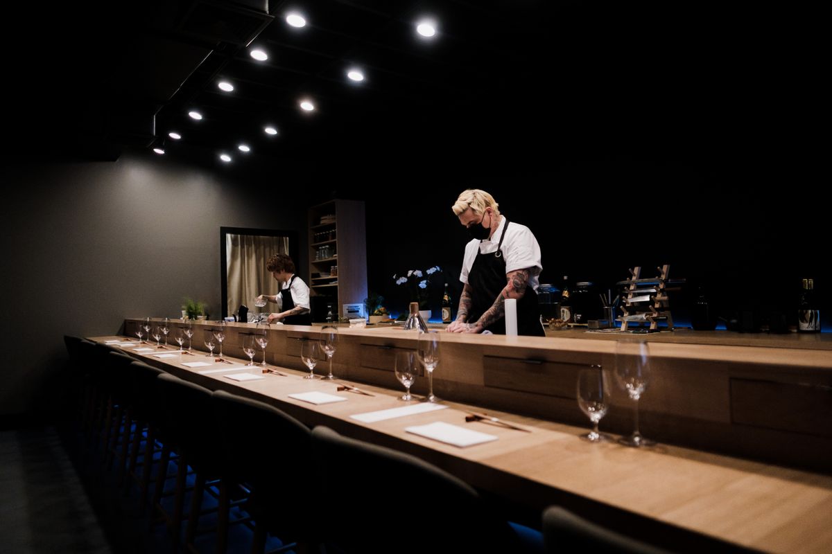 A restaurant counter being laid before service, the room still dark.