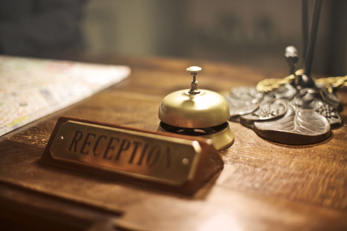 A brass service bell on a wooden reception counter.